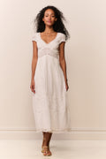 White midi dress with V-neckline, embroidered vertical panels, and tiered skirt