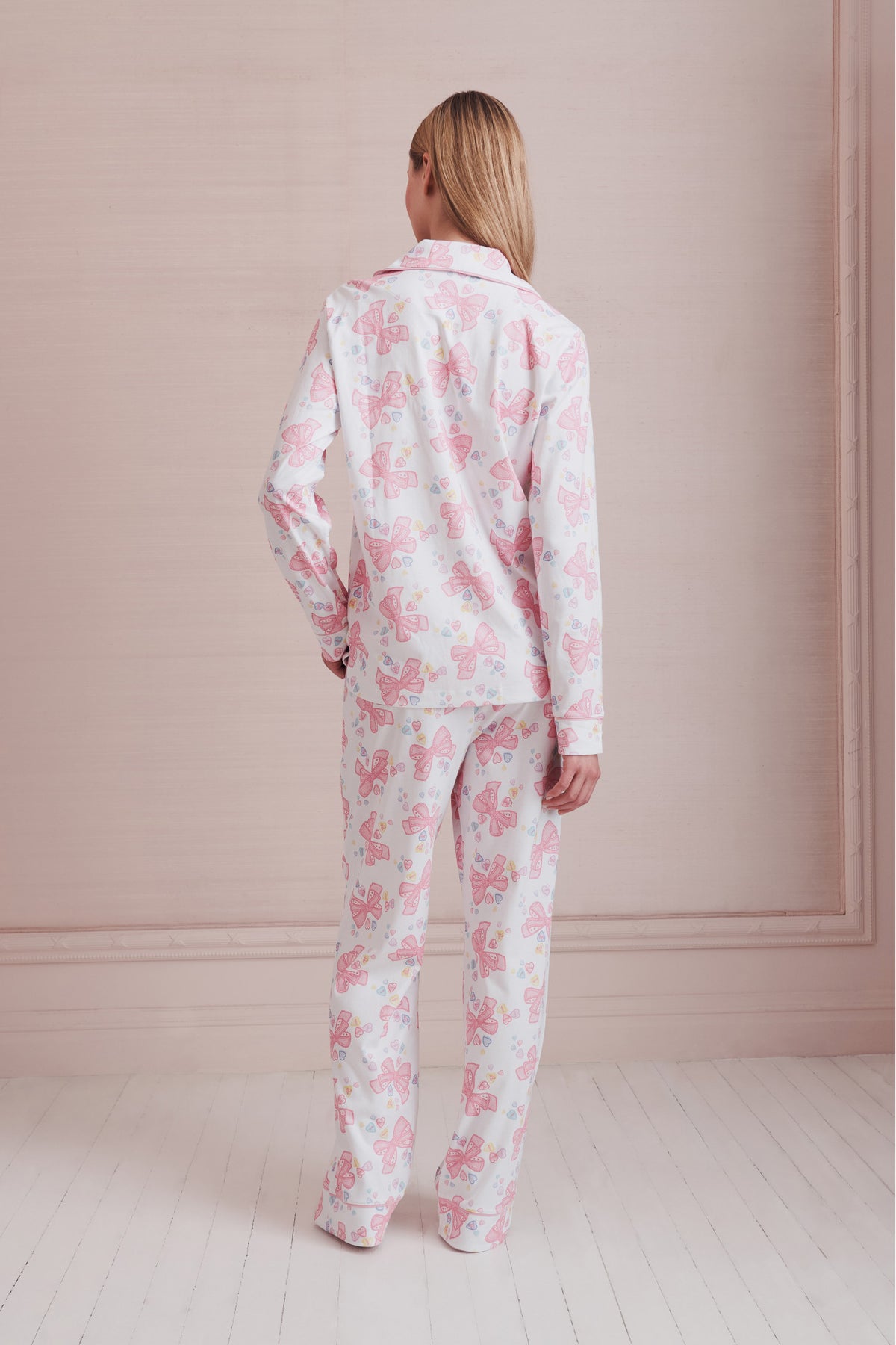 Women's long-sleeve pajama set in pink-and-white bow print, back view of top and pants