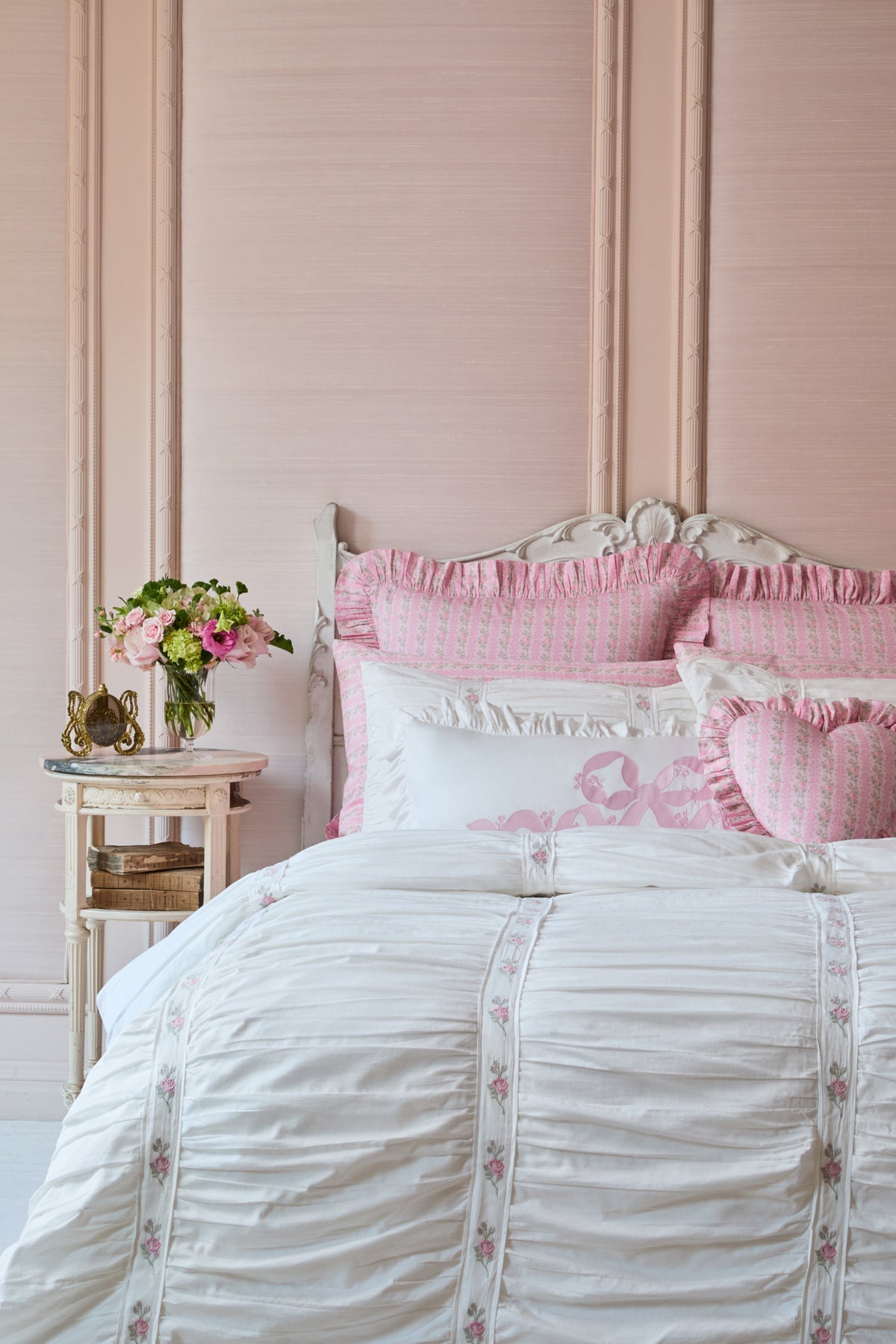 White embroidered duvet cover and shams with pink floral accents on a bed