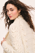 Windel ivory cardigan detail: ivory textured knit cardigan, open front with shawl collar, ribbon laced through the front, and ribbon bows on the pockets