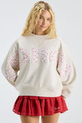 Cream mockneck crew sweatshirt with pastel “LOVE” applique; worn with red skirt