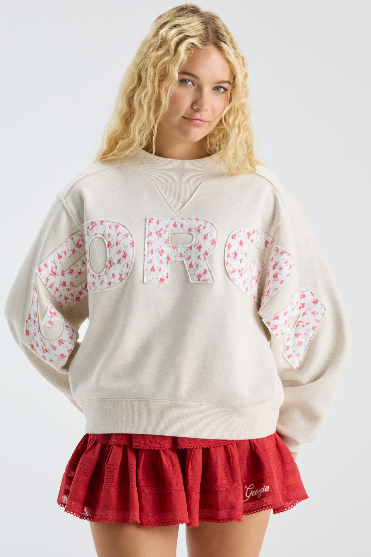 Cream mockneck crew sweatshirt with pastel “LOVE” applique; worn with red skirt