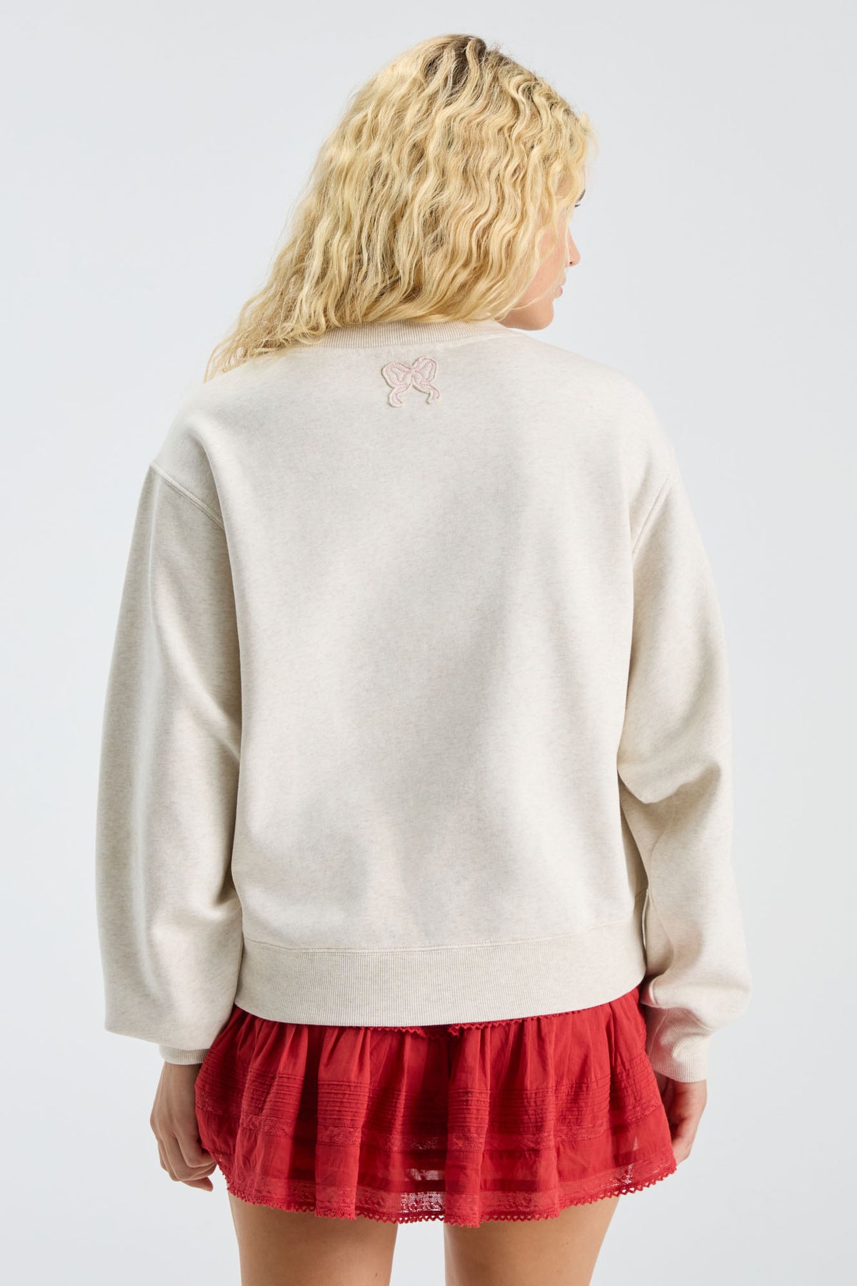 Cream mockneck crew sweatshirt with small back ribbon emblem