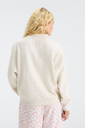 Cream mockneck crew sweatshirt with small back logo and pink floral pajama-style pants