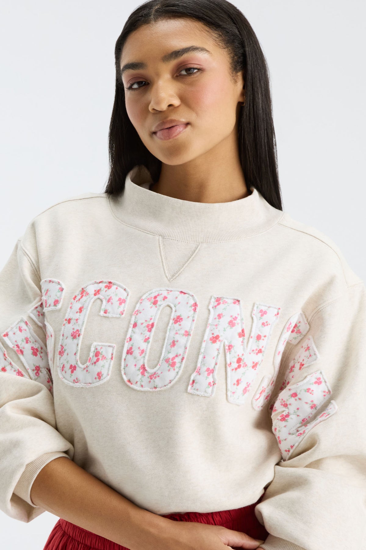 Close-up of cream mockneck crew with “FANATICS” lettering and pink floral print