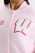 Light pink varsity jacket close-up showing red-outlined letter patch and striped collar.