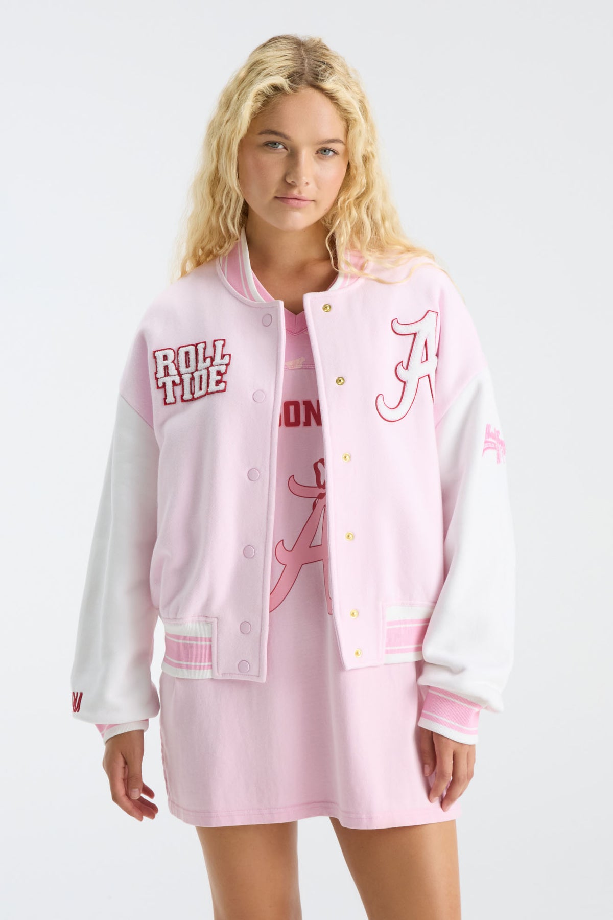 Pink varsity jacket with snap buttons, embroidered letter patch, and ribbed hem