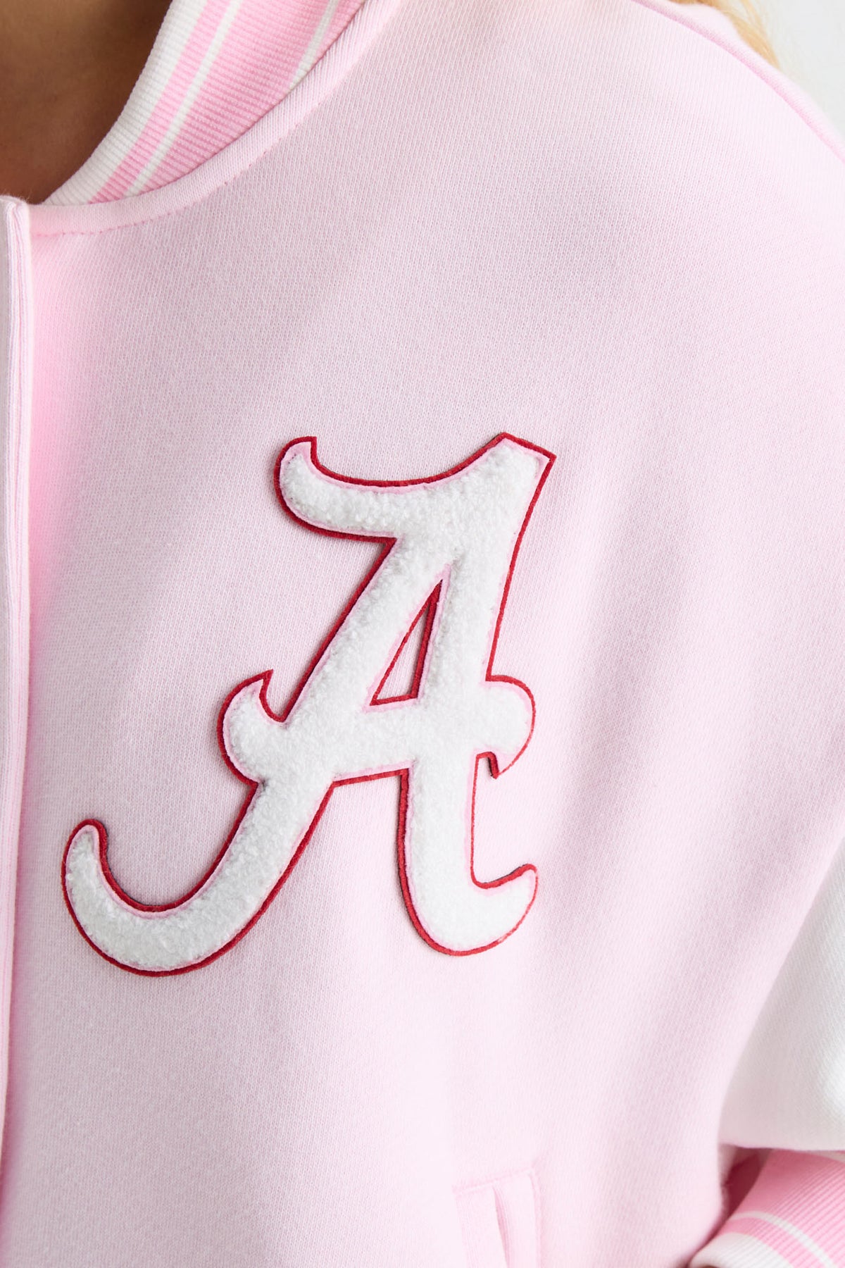 Close-up of embroidered orange letter on light pink varsity jacket sleeve front