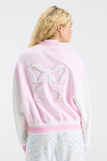 Back view of light pink varsity jacket with large bow-shaped embroidered emblem
