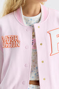 Close-up: pink varsity jacket front with embroidered orange text and “A” patch
