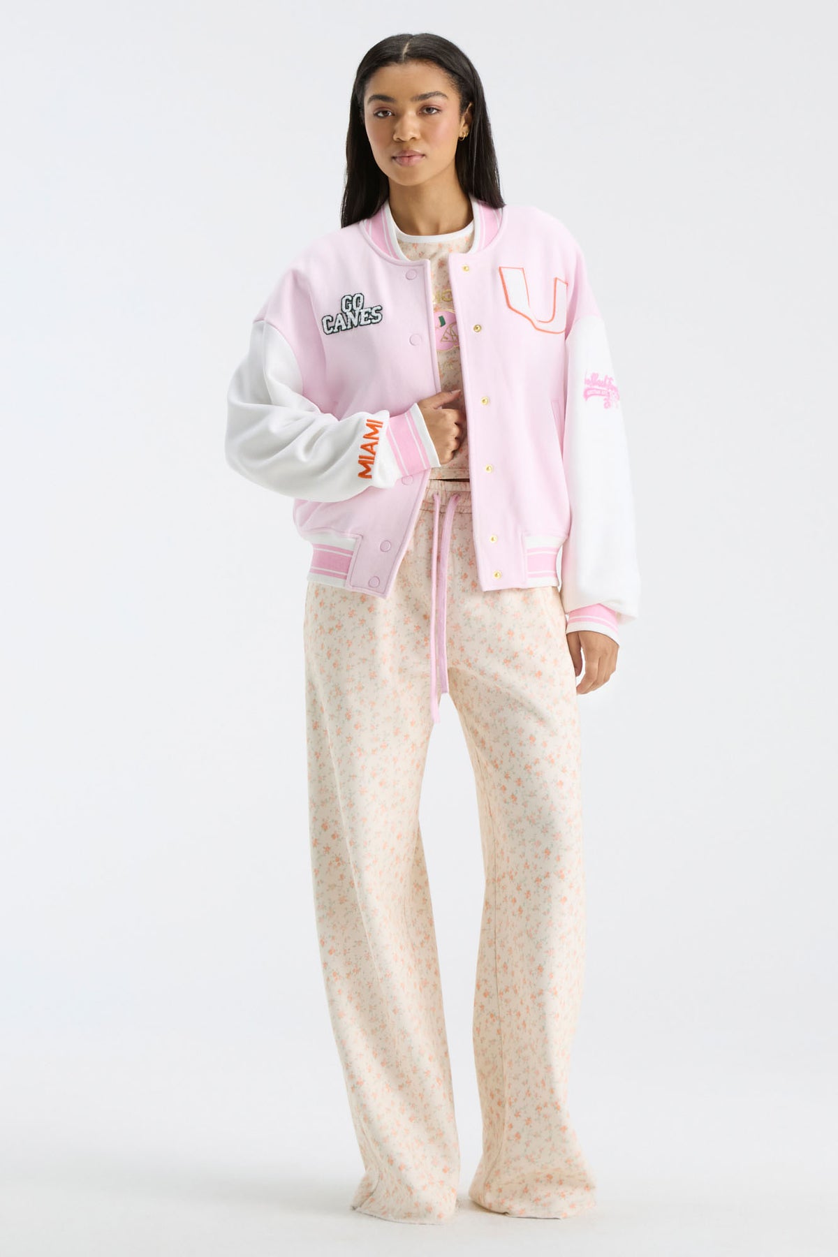 Pink collegiate varsity jacket with button front, striped cuffs, and letterman patches