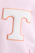 Close-up of orange-outlined T letter patch on pink varsity jacket