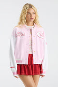 Pink varsity jacket with snap front and chest patches, paired with red skirt
