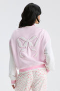 Light pink varsity jacket back with bow applique and ribbed striped waistband trim.