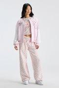 Light pink varsity jacket worn over floral pajama pants with snap front and patches.