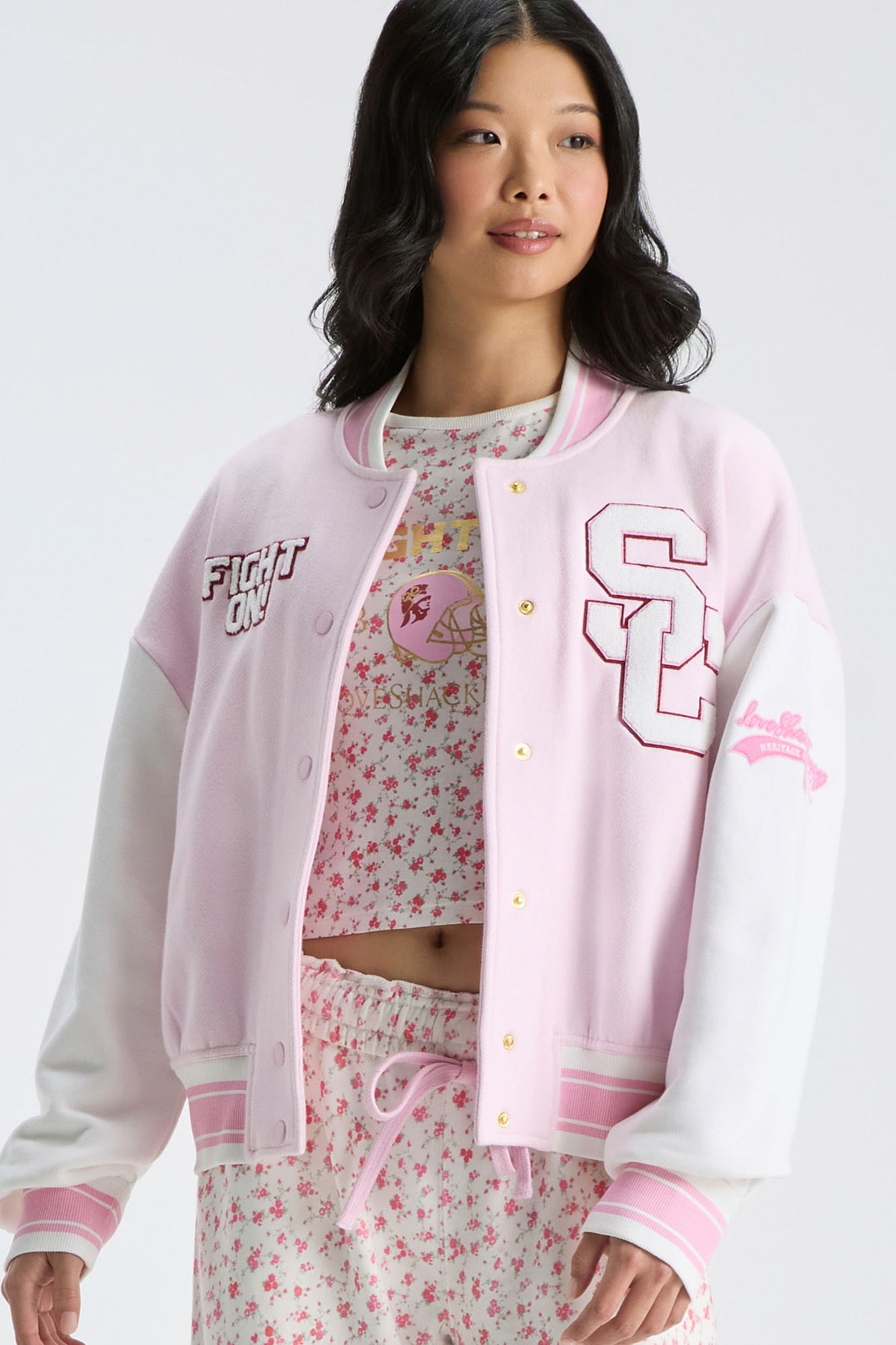 Light pink varsity jacket with snap buttons, contrast trim, and embroidered team-style graphics