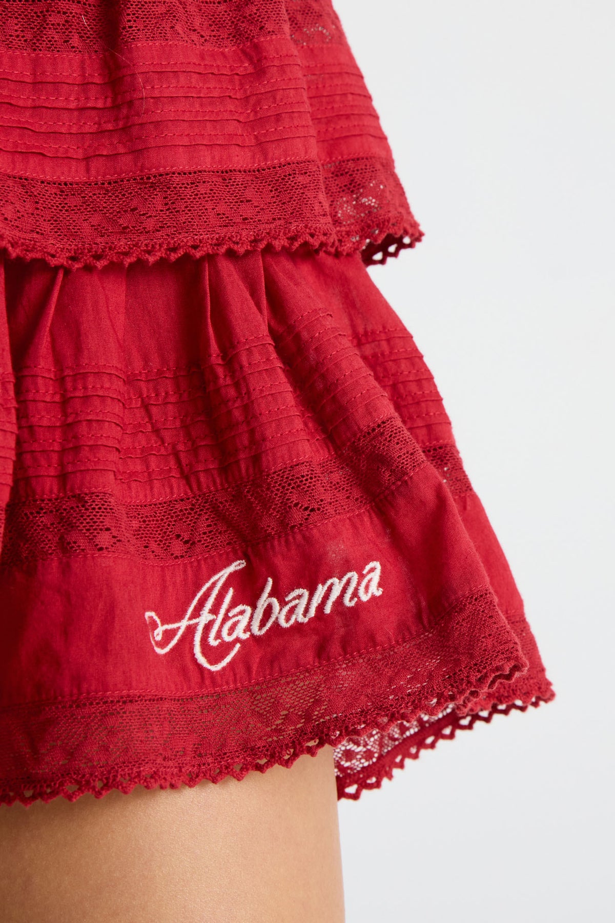 Crimson ruffle mini skirt with lace-trim hem and stitched “Alabama” script.
