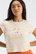 Cream floral ringer tee close-up with white crew neck trim and logo graphic