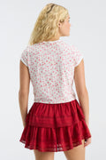 Back view of cropped pink floral ringer tee, short sleeves; red tiered skirt