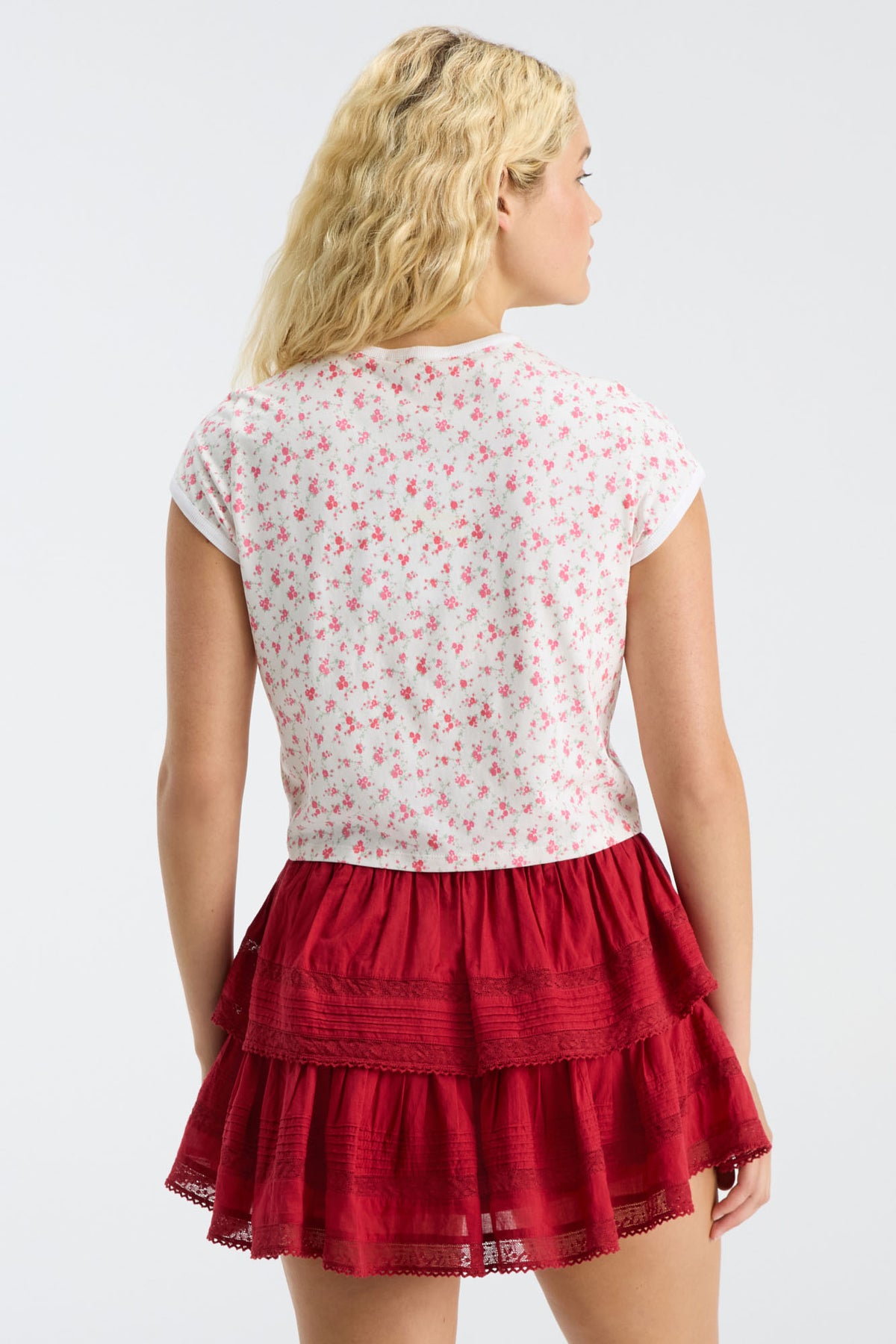 Back view of cropped pink floral ringer tee, short sleeves; red tiered skirt