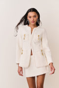 Cream tweed jacket with gold-tone charm trim, stand collar, and flap patch pockets