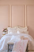 Light patchwork quilt on bed with diamond stitching and pink accents