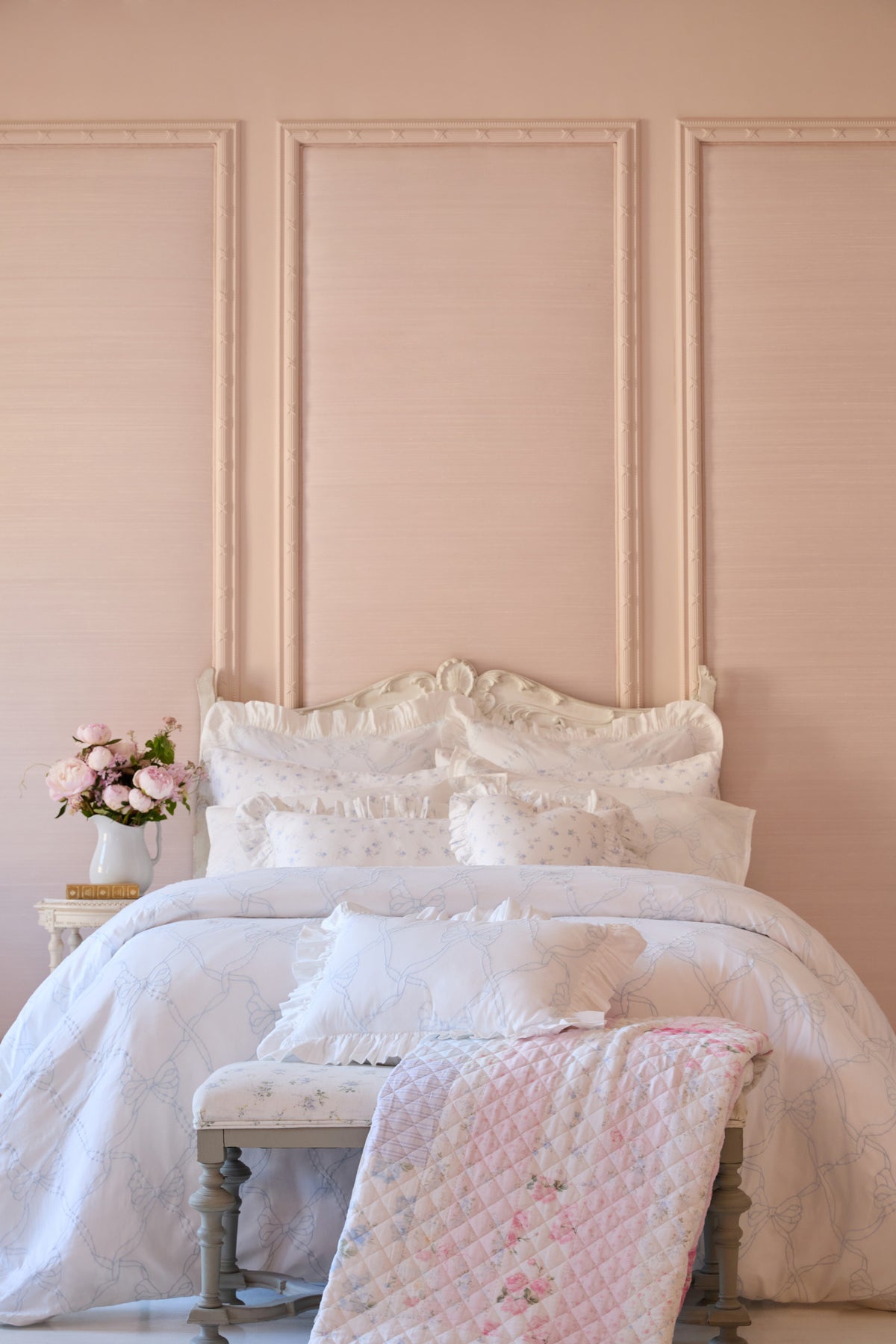 Light patchwork quilt on bed with diamond stitching and pink accents
