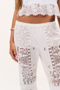 Optic white lace patchwork flared pants, close-up of front embroidered detailing
