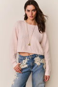 Cropped pale pink cable knit pullover sweater with textured cable pattern