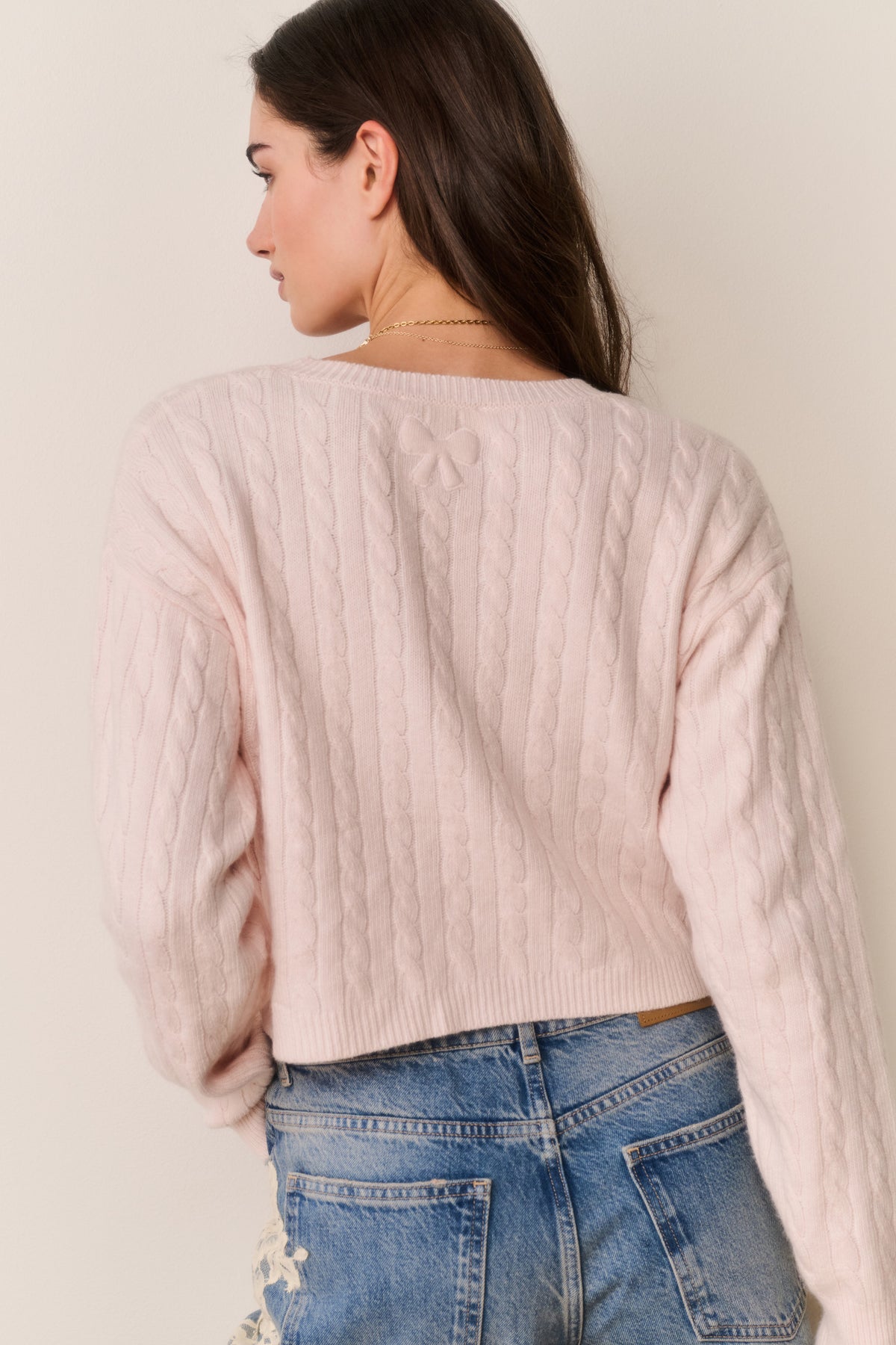 Back view cropped pale pink cable knit sweater with crew neck and long sleeves