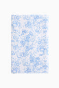 Cotton bath towel, light blue with repeating floral bow pattern, plush terry surface.
