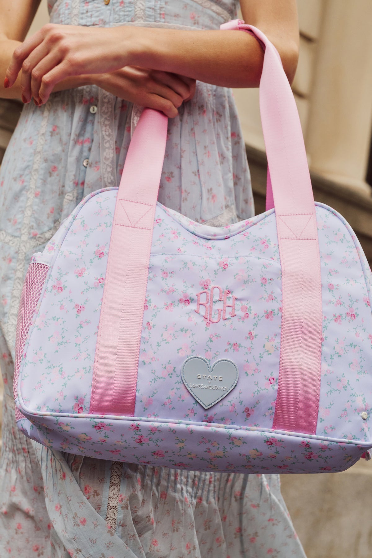 Floral diaper tote with pink trim, heart emblem, and front pocket panel