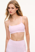 Light mauve bow-print sports bra with thin straps, model facing forward