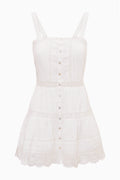 White cotton mini dress with spaghetti straps, button-front panels, tiered tiers, lace hem