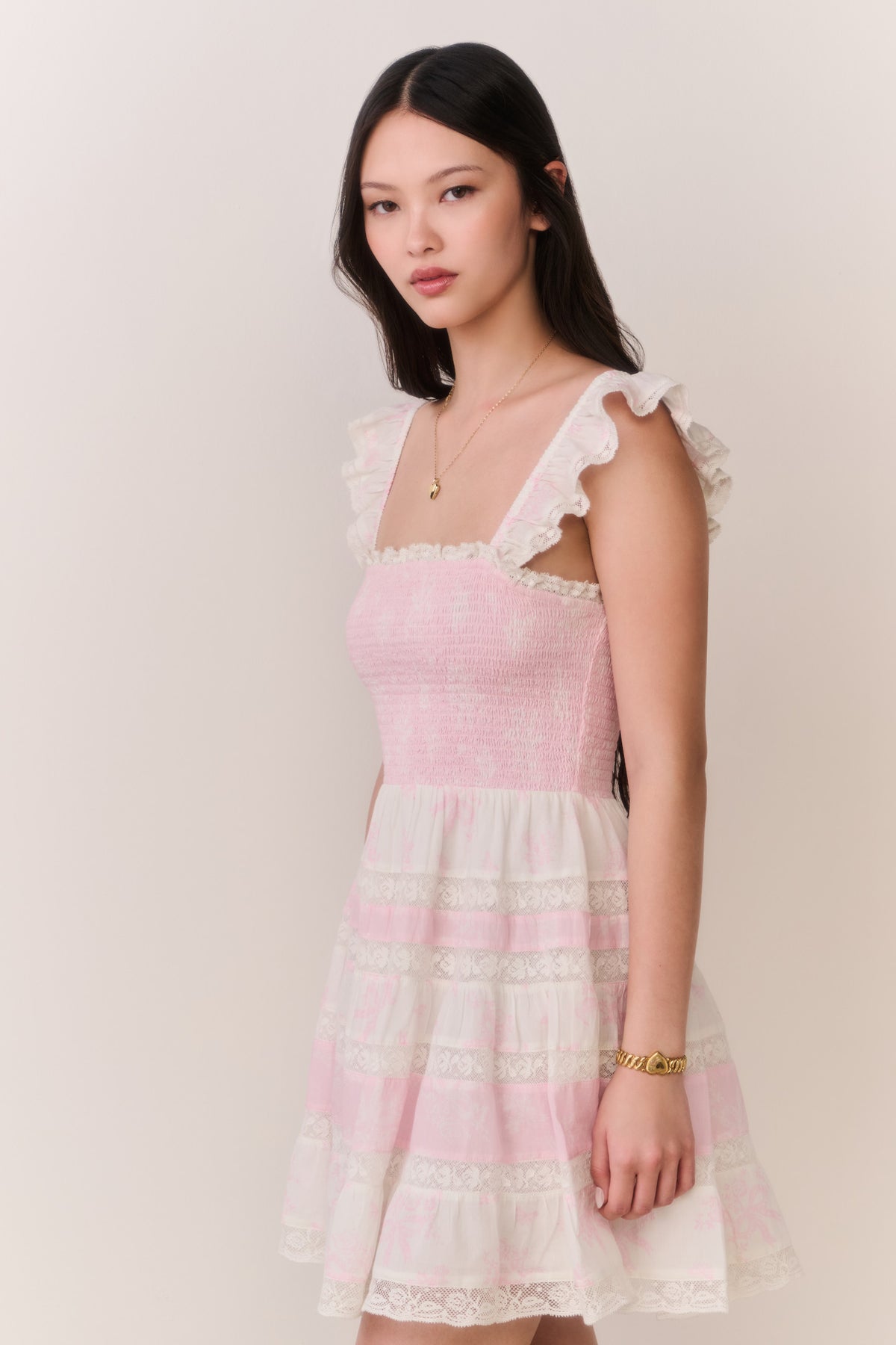 Pink mini dress with ruffled square neckline, tiered skirt, and lace-trim accents