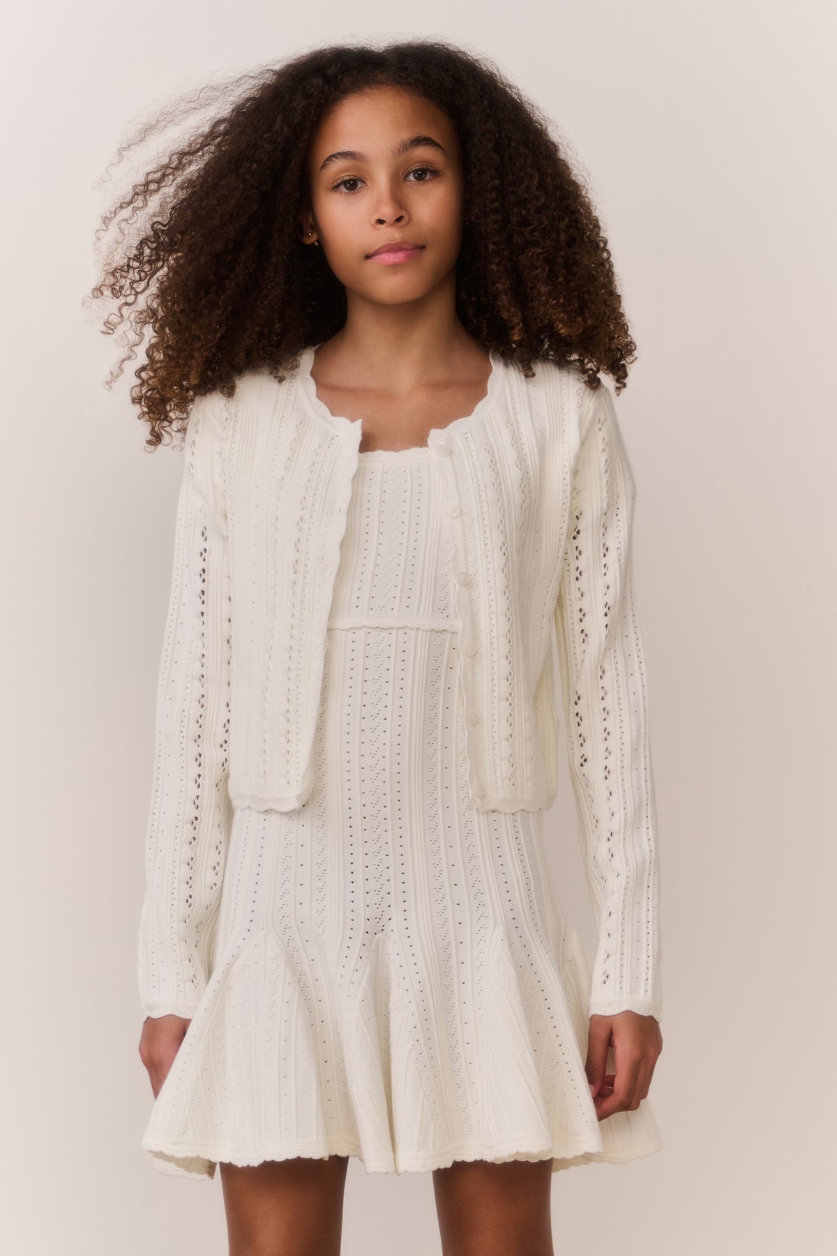 White pointelle cardigan with long sleeves and open front, vertical knit texture.