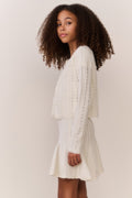White pointelle cardigan with long sleeves and open front, textured knit finish.