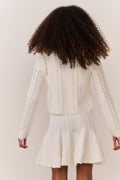 White pointelle knit cardigan with long sleeves, open front, scalloped hem detail.