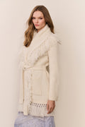 Ivory wrap cardigan with fringe shawl collar and tied waist, ribbed knit texture.