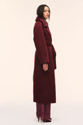Side view of dark merlot faux fur collar wool coat with tied waist belt.