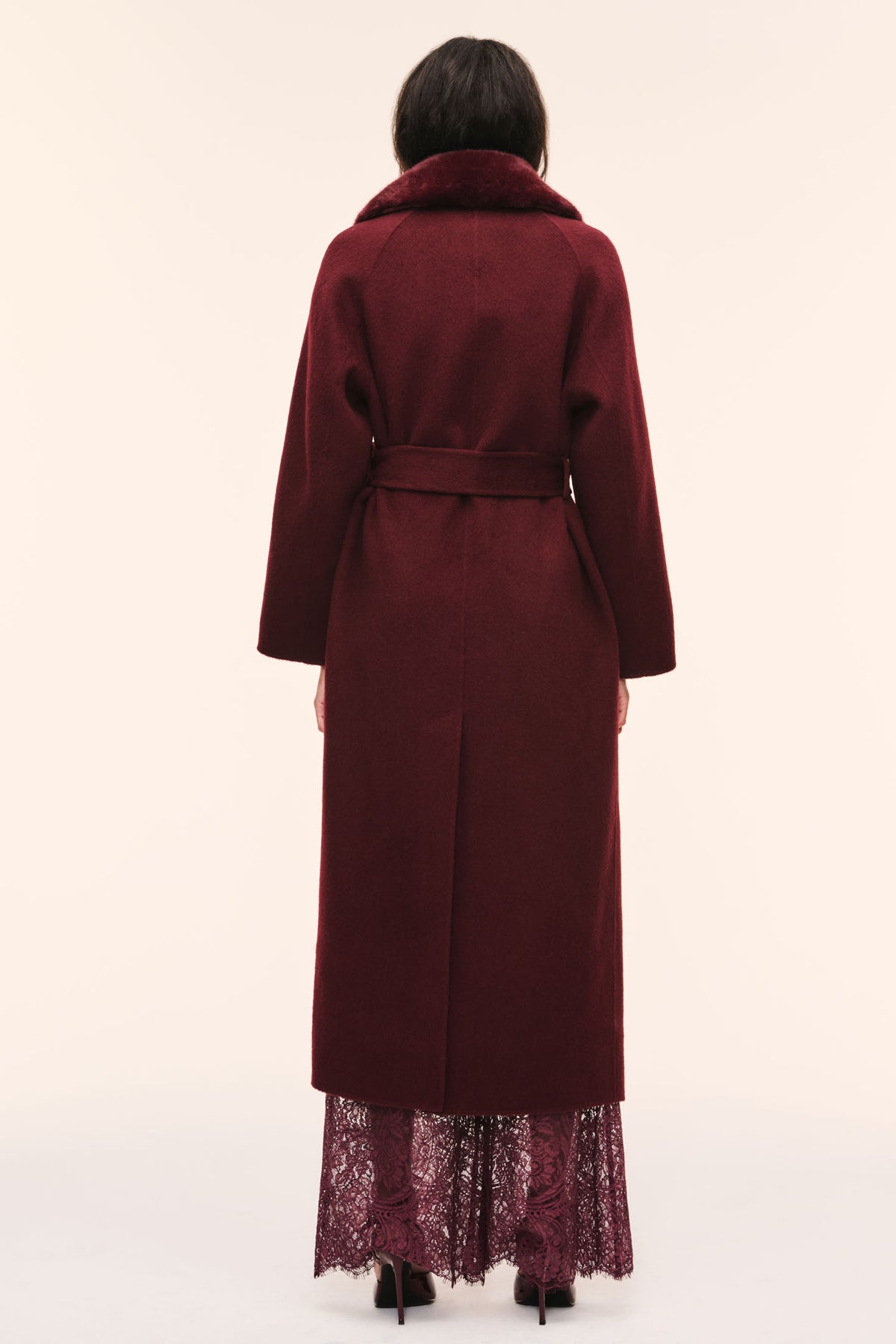 Back view of dark merlot long wool coat with faux fur collar and tied waist belt.