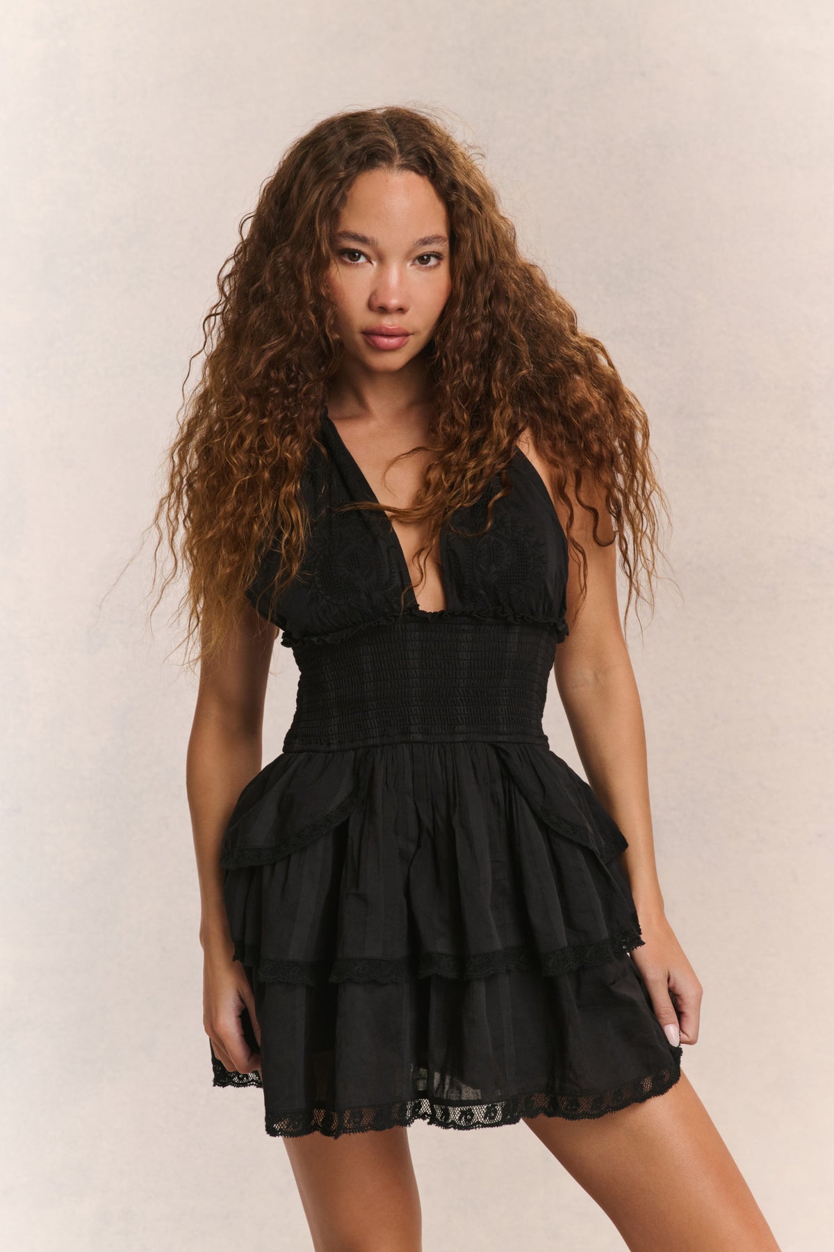 Black halter mini dress with V neckline, tiered skirt, and scalloped lace trim