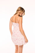 White mini dress with pink floral print, lace-trim back straps, side back view.