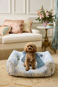 Printed dog bed with blue floral cover and small dog sitting on the cushion