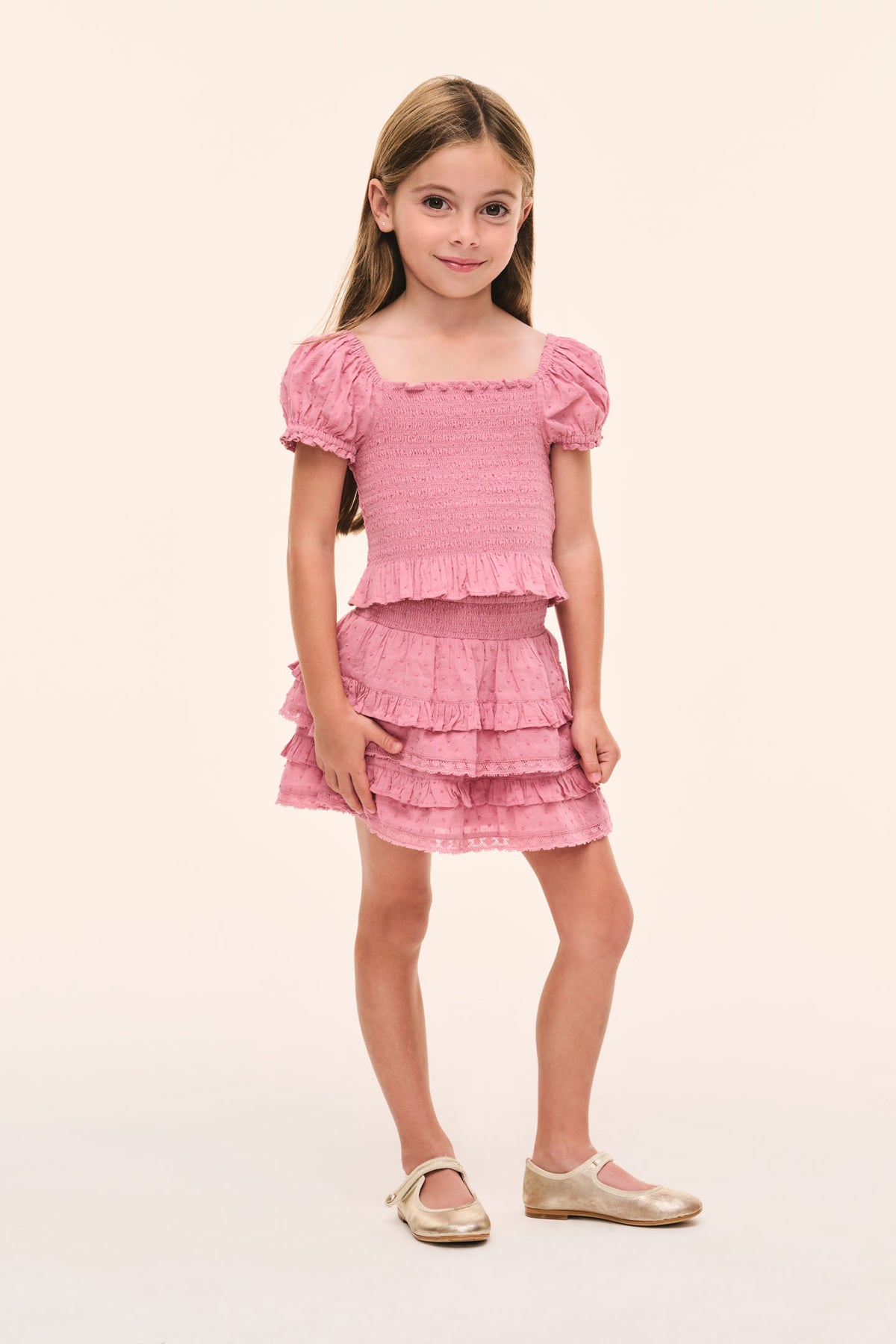 Girls’ pink smocked top with tiered ruffle hem and puff sleeves, full view