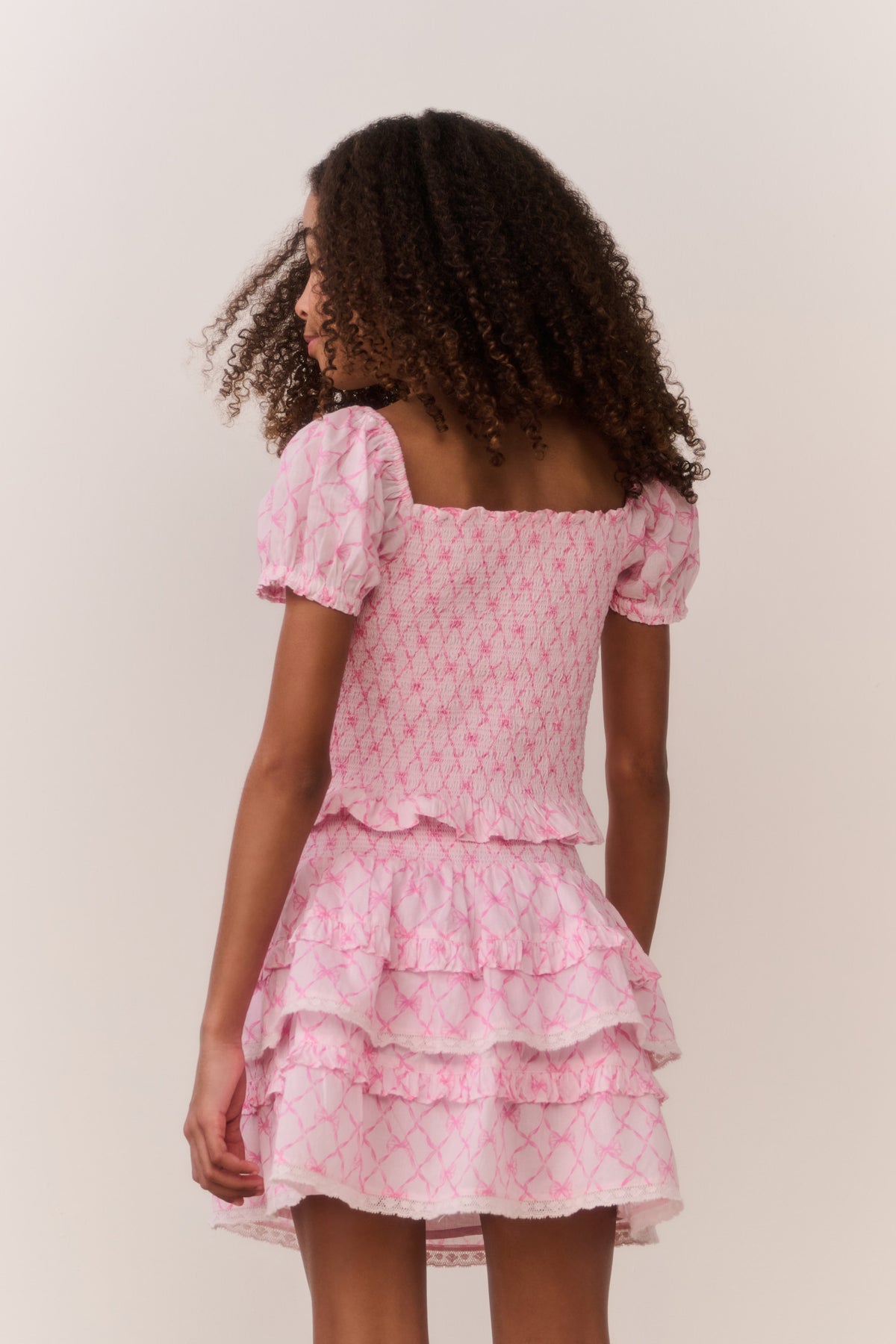 Pink short-sleeve top, lattice print, layered ruffle skirt detail from back