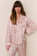 Woman wearing a pink floral pajama set against a plain background