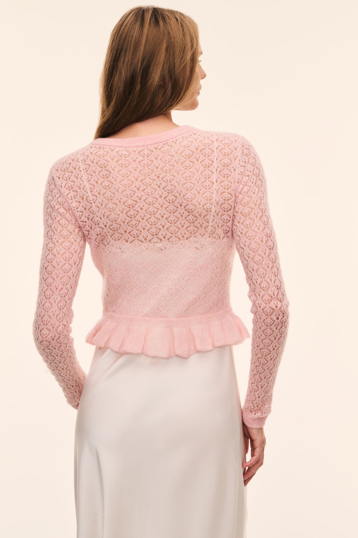 Light pink pointelle cardigan back view with ruffle peplum hem, long sleeves