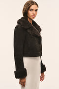 Dark cropped shearling jacket with plush collar, drawstring detail, and fur cuffs