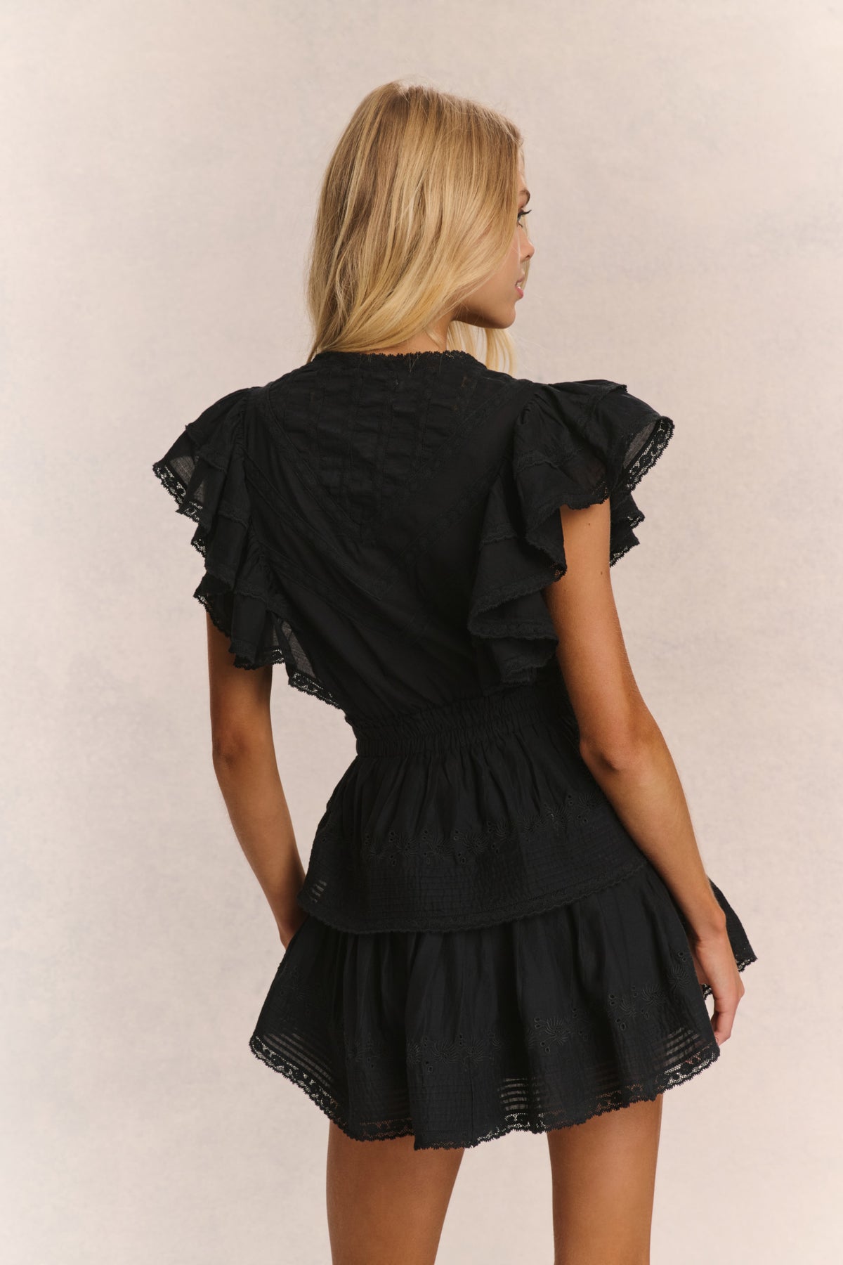 Black backless-style mini dress with tiered ruffle skirt and flutter sleeves